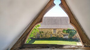 Una ventana triangular con un edificio de piedra visible a través de ella.