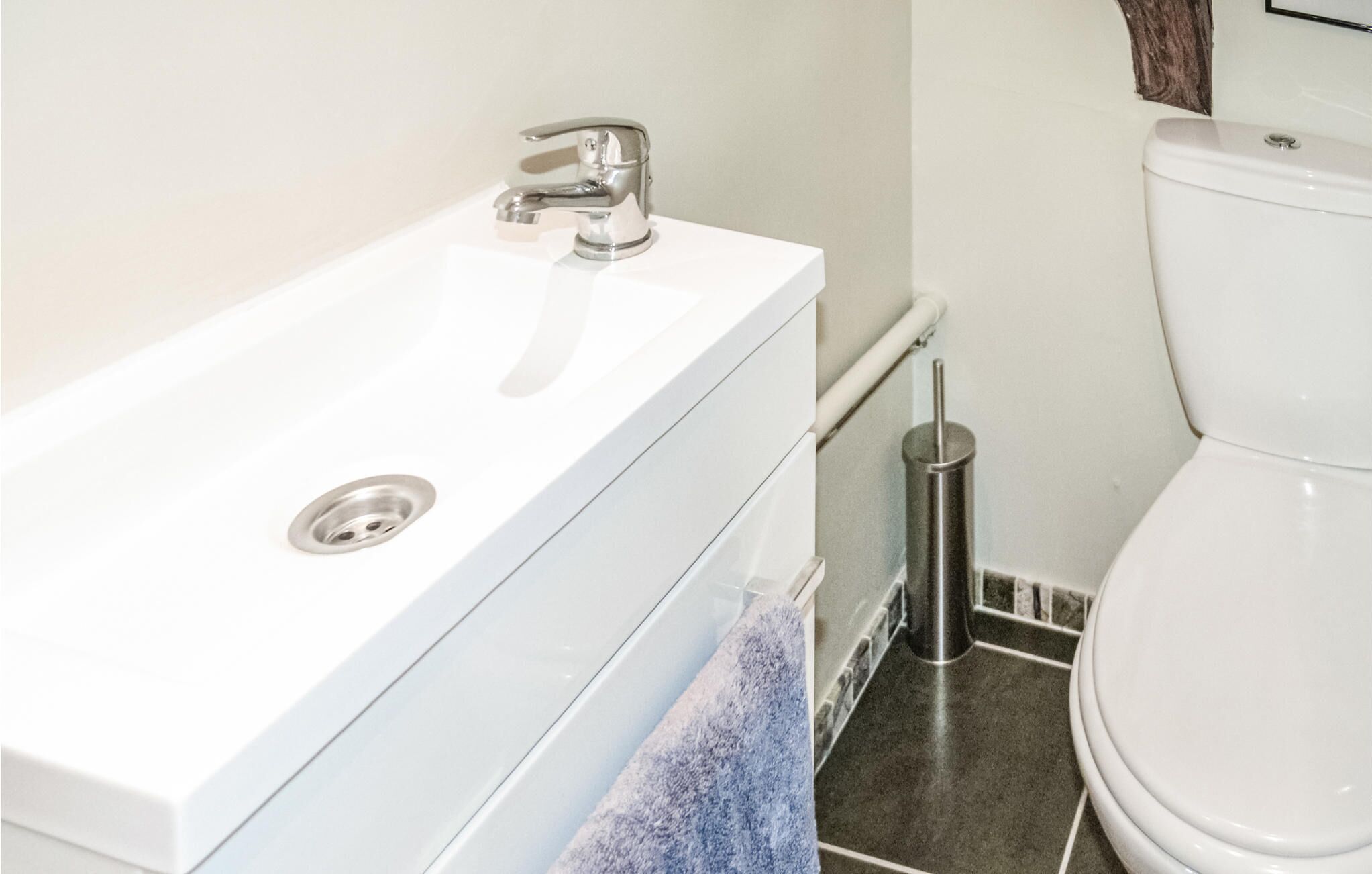 Une salle de bain avec un lavabo blanc, des toilettes et une poubelle.