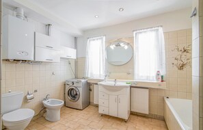 Ein modernes Badezimmer mit Toilette, Bidet, Waschmaschine, Waschbecken und Badewanne.