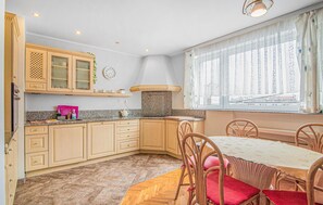 Eine kleine Küche mit Holzschränken, einer Arbeitsplatte aus Granit und einem Essbereich mit Tisch und Stühlen.