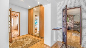 Ein Korridor mit Holzboden, einem großen Spiegel und Blick in einen Raum mit Steinwand und einer Couch.