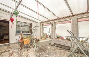 Ein überdachter Patio-Bereich mit Schaukel, Sitzgelegenheiten und Blumentöpfen.