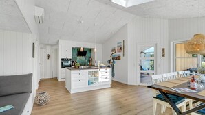 A spacious kitchen with white cabinetry, a central island, and a dining area with a wooden table and chairs.