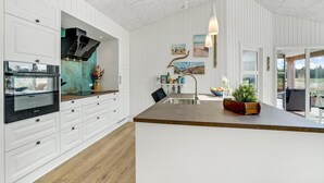 A modern kitchen with white cabinetry, a built-in oven, and a large island with a sink.
