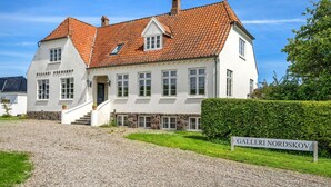 Ein zweistöckiges Gebäude mit weißer Fassade und rotem Ziegeldach, beschriftet mit 'GALLERI NORDSKOV'.