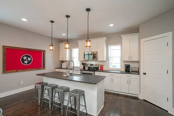 Enjoy cooking in this well-equipped kitchen with a central island, oven, and stainless steel sink.