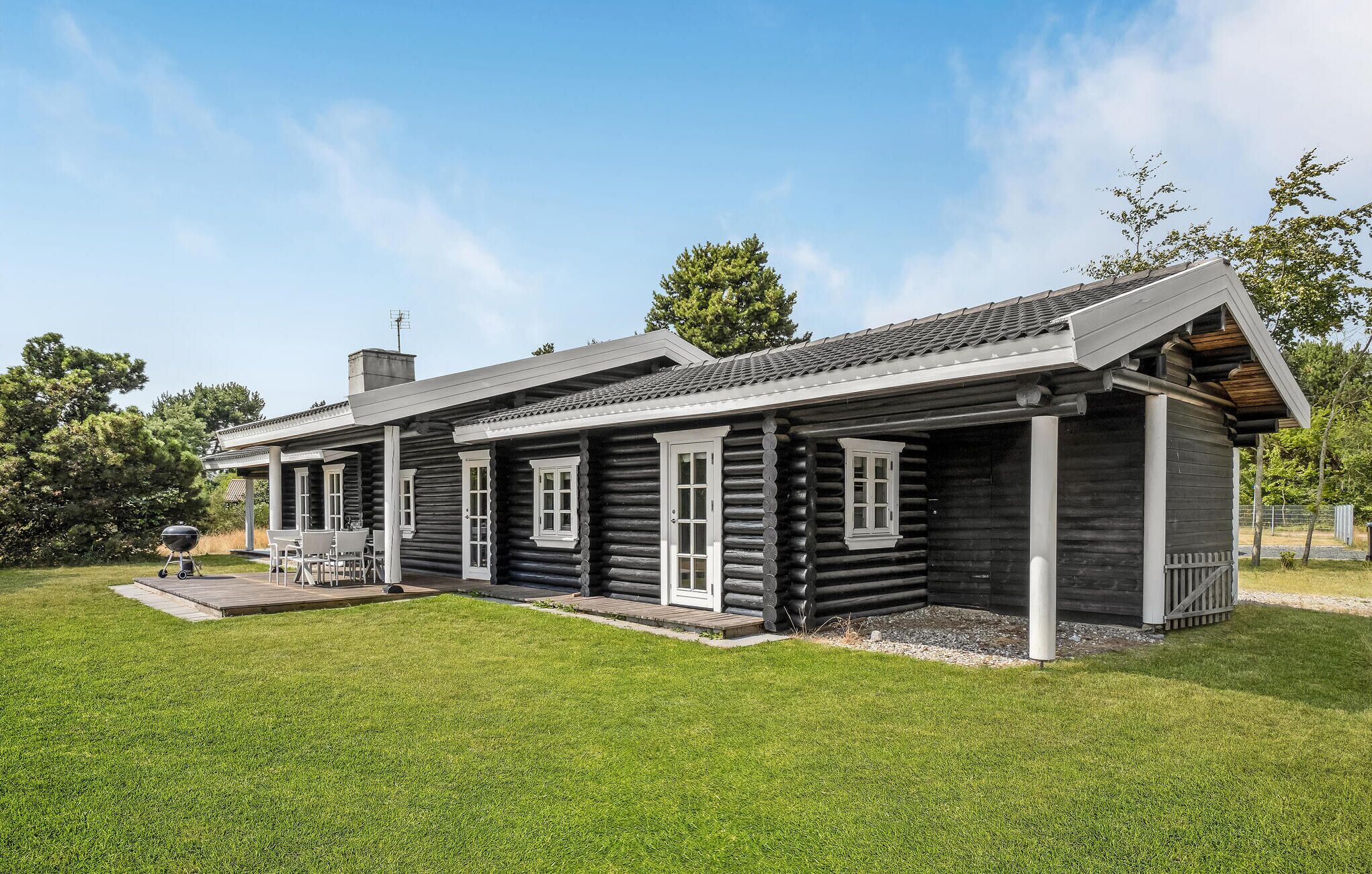 Eine Holzhütte mit Veranda und Grillplatz.
