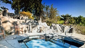 Piscina con escalones, rodeada de muros de piedra y sillas.