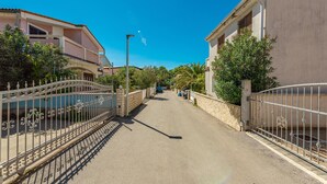 A narrow street flanked by residential buildings with balconies and fences.