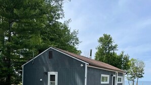 A single-story building with a dark exterior, a white door, and a small window. - Shore Cliff Cottage  (Ashtabula)