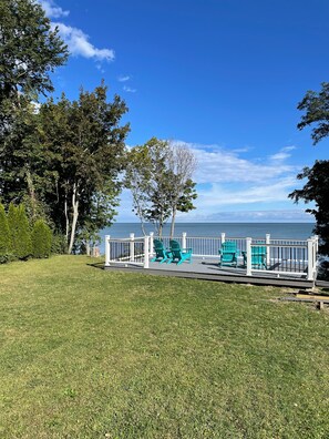 A deck with a railing, green chairs, and a view of the sea. - Shore Cliff Cottage  (Ashtabula)