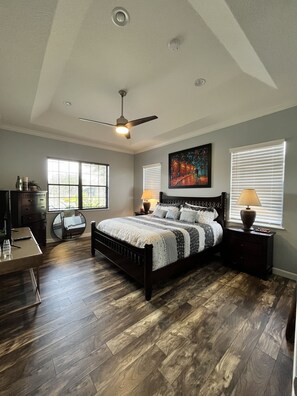 Cozy retreat with a large bed, nightstands, and a ceiling fan, offering a comfortable space to rest.