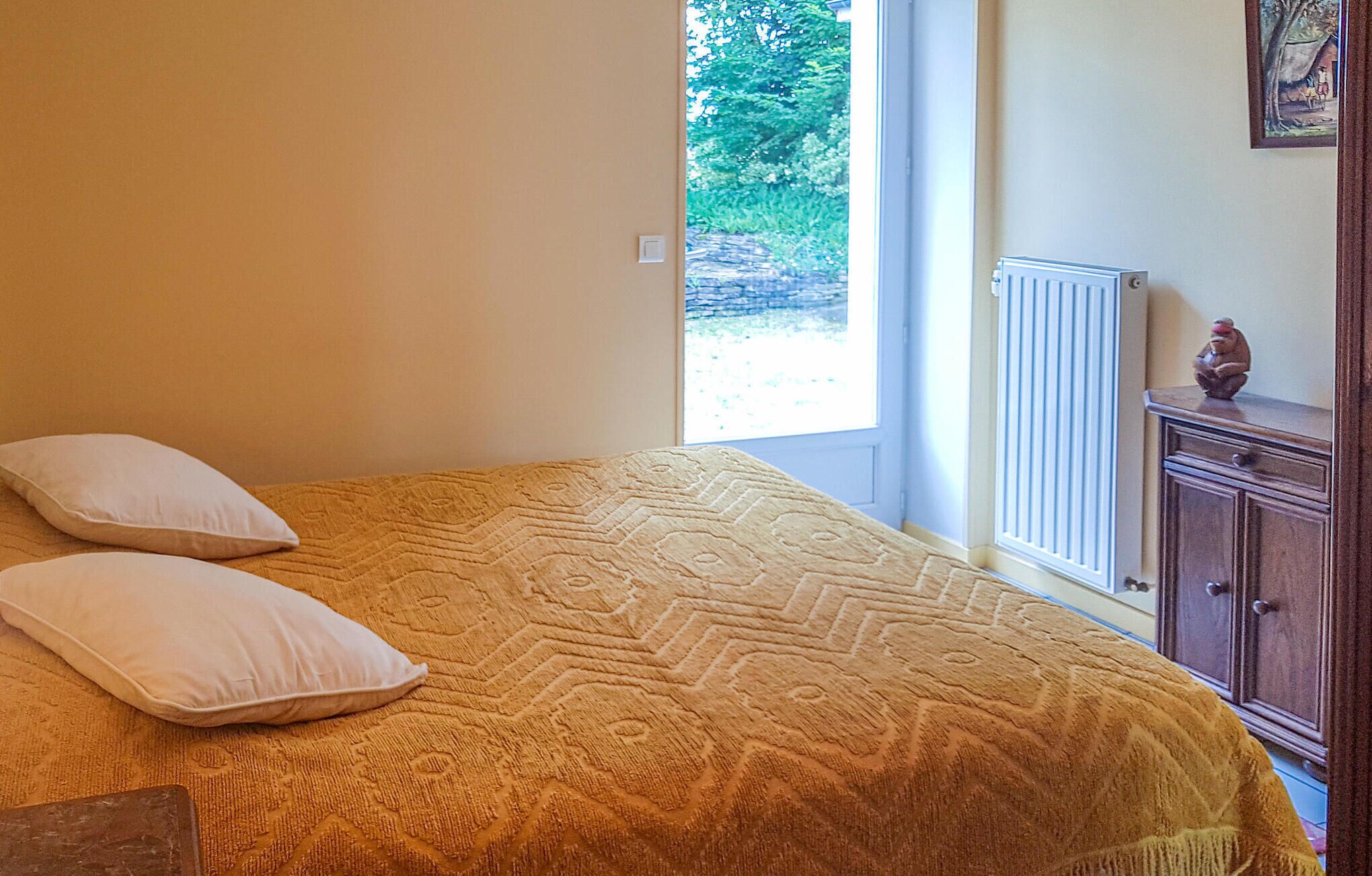 A bedroom with a bed, two pillows, a radiator, and a wooden cabinet.