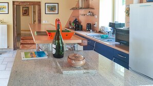 A kitchen with a granite countertop, a wine bottle, a ceramic jar, and a dining area with a table and chairs.