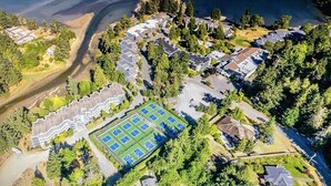 An aerial view of a residential area with houses, a tennis court, and a beach. - Pacific Shores Resort - Oceanfront & Amenities Included!!! (Nanoose Bay)