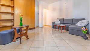 A modern living room with a grey sofa, wooden sideboard, and a round wooden table.