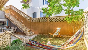 A hammock, a striped beach chair, and a staircase leading to an upper level.