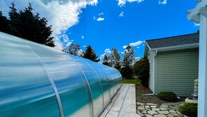 A greenhouse structure with a transparent covering, adjacent to a house with a stone pathway and a small garden area. - *PRIVATE LEISURE POOL* 3bd 2ba Home Near Bypass&Amenities (Kalispell)