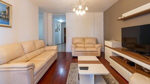 A living room with a beige sofa, a matching armchair, a coffee table, a TV stand, and a chandelier. - Gorgeous apartment in Pula with WiFi (Pula)