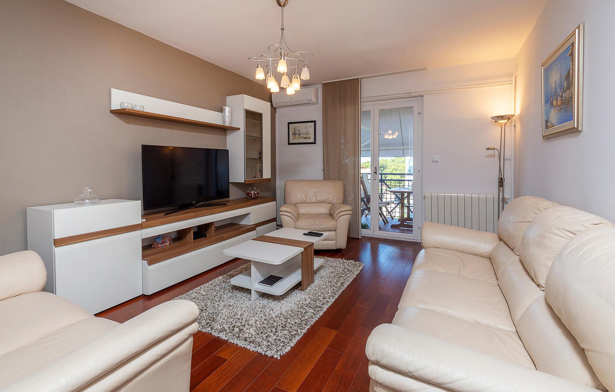 A modern living room with a flat-screen TV, a sofa, a chair, and a coffee table.