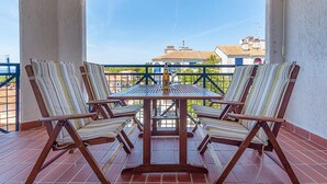 A terrace with four striped chairs and a table, featuring a bottle of liquor. - Gorgeous apartment in Pula with WiFi (Pula)