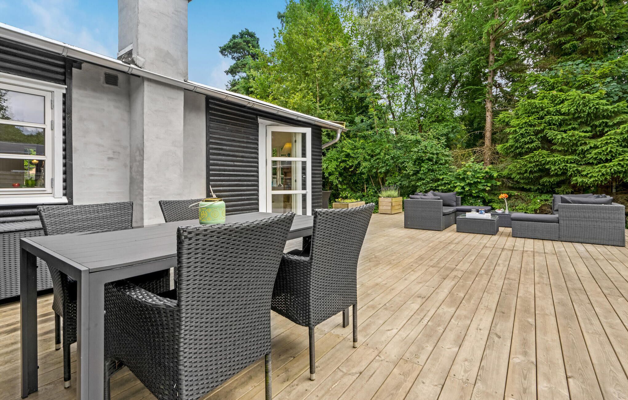 Une terrasse extérieure avec une table et des chaises, un ensemble de canapés et une plateforme en bois.