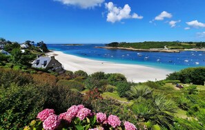 A coastal landscape with a sandy beach, boats in the water, and lush greenery. - Nice home in Saint-Pabu (Saint-Pabu)