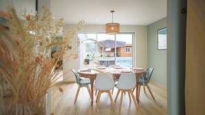 Un coin repas avec une table ronde dressée pour quatre personnes, entourée de chaises aux pieds en bois.
