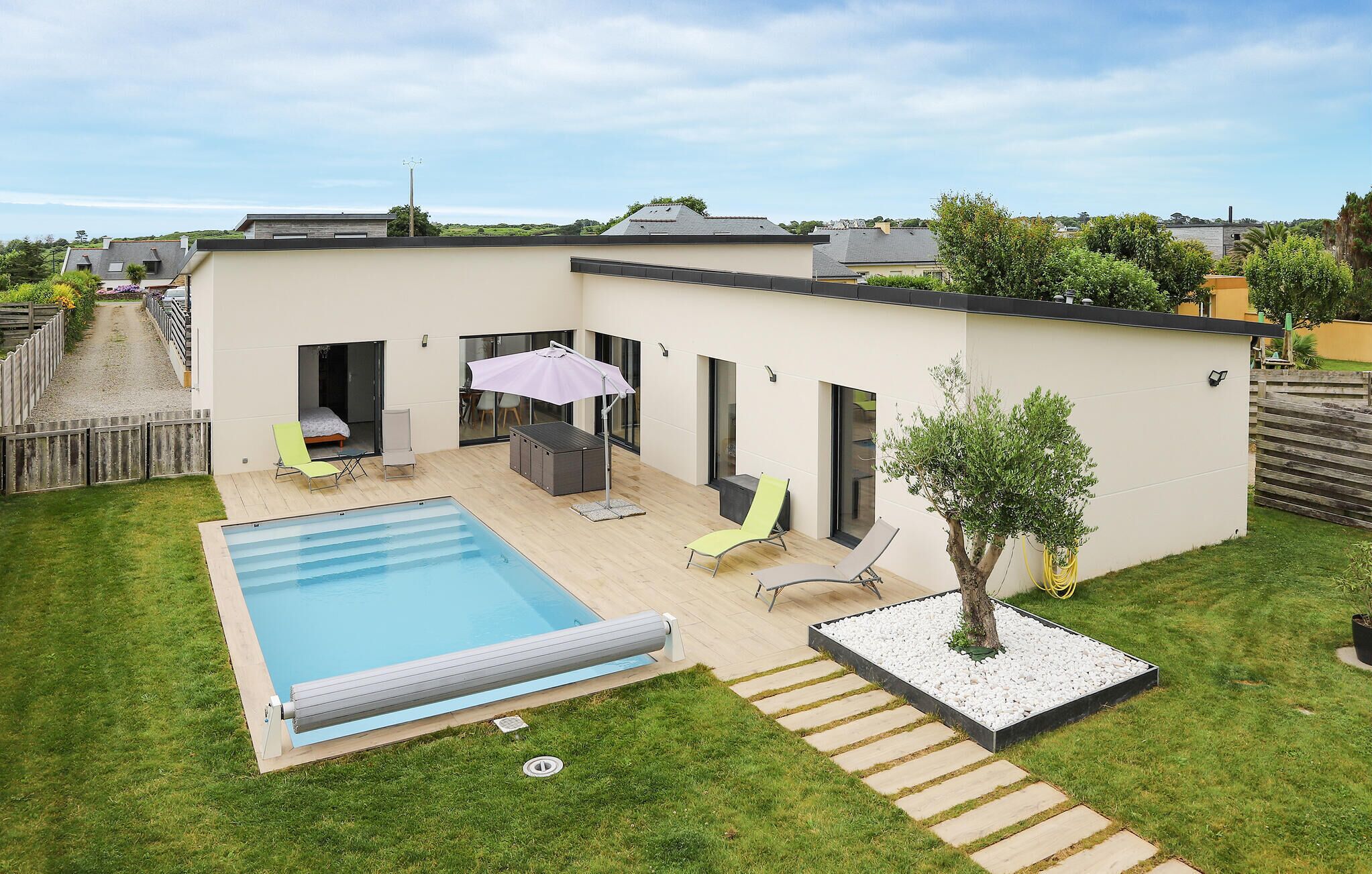 Ein modernes Haus mit Swimmingpool, Sitzgelegenheit im Freien und einem kleinen Garten.
