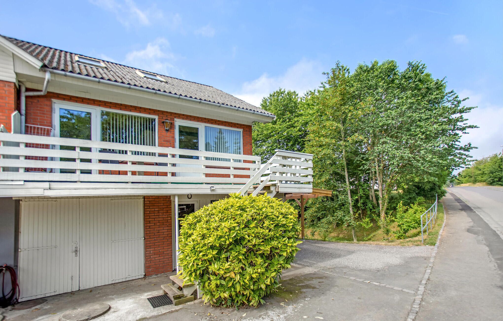 A two-story house with a white balcony, a garage, and a well-maintained garden.