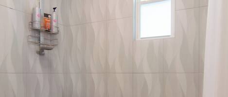 A shower area with a towel rack, a small table, and a window.