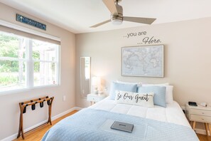 Une chambre à coucher avec un lit, un bureau, une carte accrochée au mur et une pancarte au-dessus de la fenêtre.