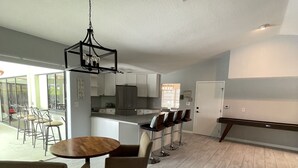 A spacious kitchen with modern appliances, a dining area with a round table and chairs, and a large window providing natural light. - Punta Gorda Isles Home -Waterfront Canal,Private Pool, Bird Section, gulf access (Punta Gorda)