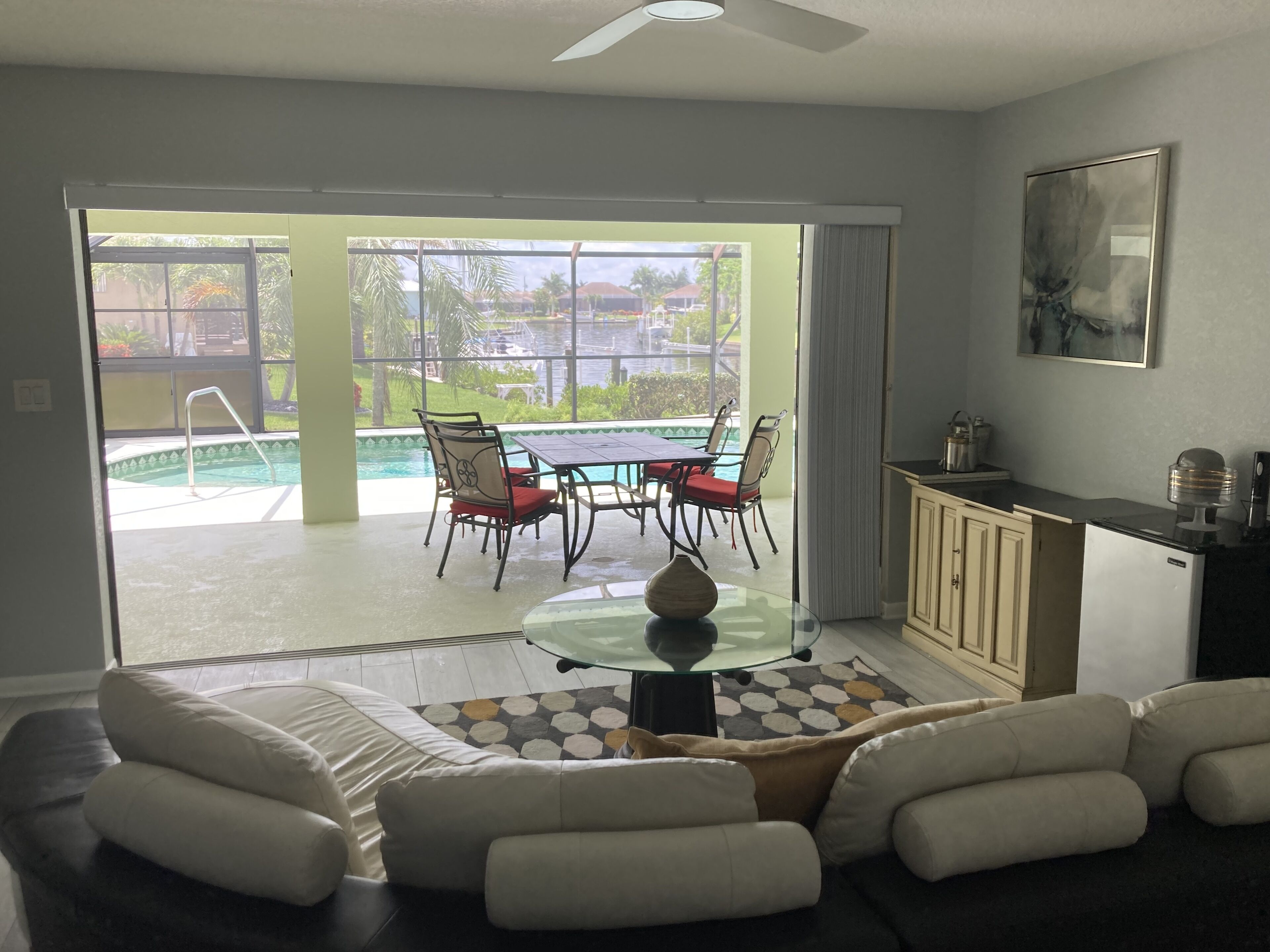 Una sala de estar con una mesa de vidrio, un sofá y vistas a una piscina y un área de estar al aire libre.