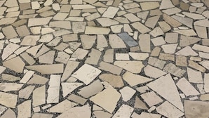 Un suelo de baldosas con un diseño de mosaico, una puerta y una pared con textura similar a la de un panal.