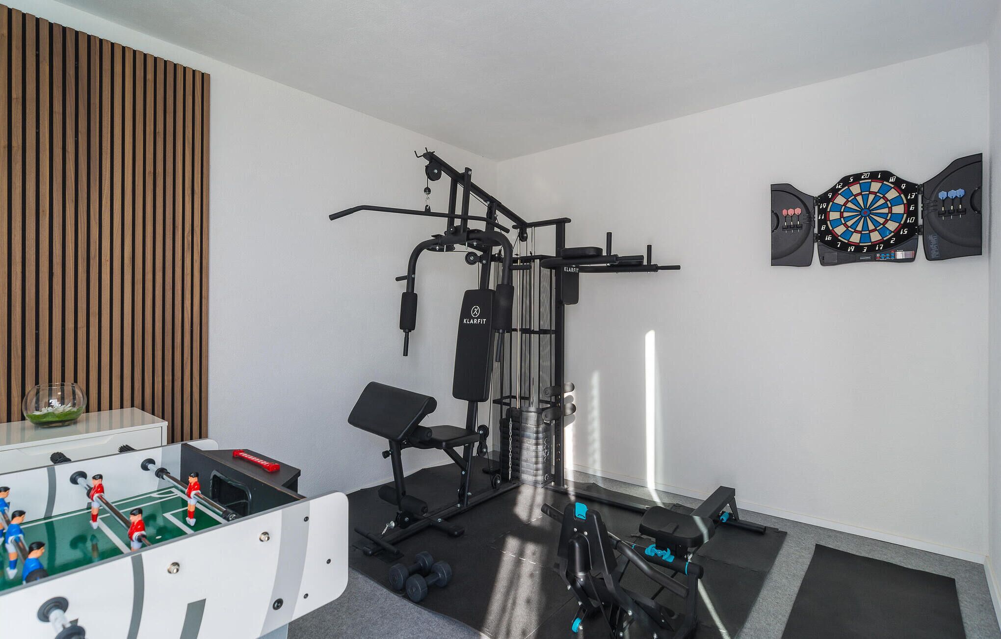 A home gym with a pull-up bar, weight bench, and dumbbells.