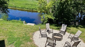 A patio with outdoor seating and a pond. - Relax N Rentals Waterfront 3BR UP Algoma WI Kayaks Grill Fire Pit (Algoma)