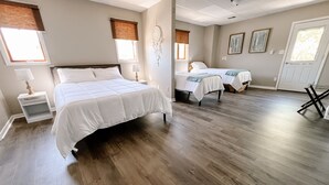 A hotel room with a large bed, two smaller beds, a dreamcatcher, and a view of the outside. - Relax N Rentals Waterfront 3BR UP Algoma WI Kayaks Grill Fire Pit (Algoma)