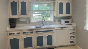 A kitchen with white cabinets and blue accents, a window, a sink, a coffee maker, and a microwave. - Cute house close to hospital, UW, shops, bike trails and restaurants (Madison)