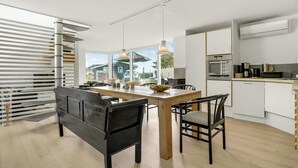 Una cocina moderna con comedor, que incluye una mesa de madera, sillas negras y un ventanal con vistas al exterior.