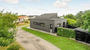 Una casa moderna con fachada gris, techo inclinado y entrada con camino pavimentado.