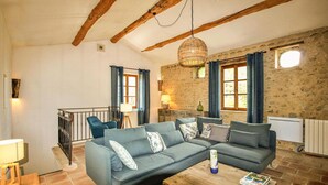 Una sala acogedora con un sofá modular, una mesa de centro de madera y una lámpara colgante.