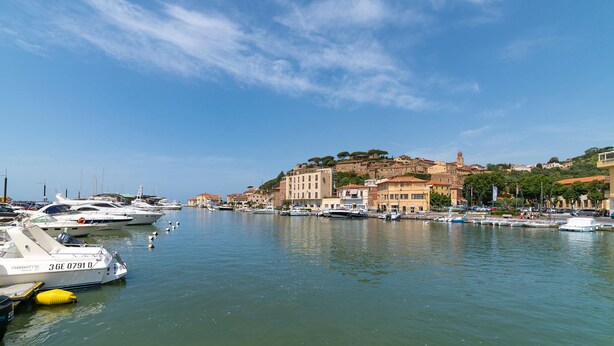 A marina with boats docked, a town with historic buildings, and a clear sky. - Lovely home in Castiglione della Pesc (Castiglione della Pesc)