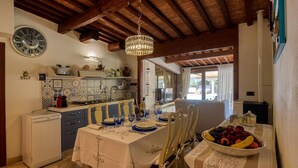 A dining area with a table set for four, a fruit bowl, and a kitchen in the background. - Lovely home in Castiglione della Pesc (Castiglione della Pesc)