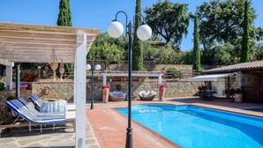 A pool area with lounge chairs, a pergola, and a stone wall. - Lovely home in Castiglione della Pesc (Castiglione della Pesc)