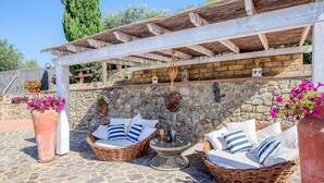 A patio area with wicker furniture and stone walls. - Lovely home in Castiglione della Pesc (Castiglione della Pesc)