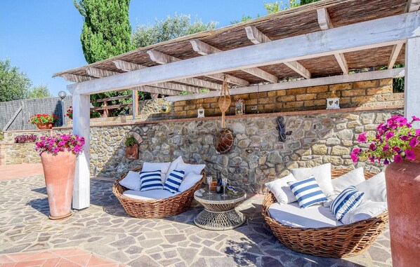 Un patio con mobiliario de mimbre y paredes de piedra.