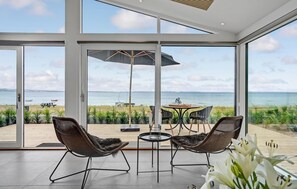 A spacious balcony with two wicker chairs, a small round table, and a large umbrella. The balcony overlooks a beach and the sea. - Nice home in Rønde with house sea view (Rønde)