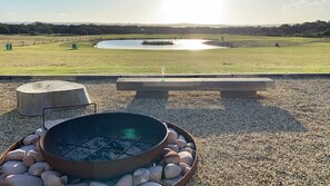 An outdoor seating area with a fire pit, a bench, and a view of a lake. - Majuba Country Lodge (Kalgan)