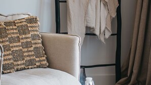 A cozy room with a sofa, a woven pillow, a black metal headboard, and a table with a tray holding apples, a bottle, and a bowl of cereal. - Majuba Country Lodge (Kalgan)
